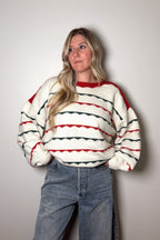 Person wearing a striped sweater and jeans against a plain background