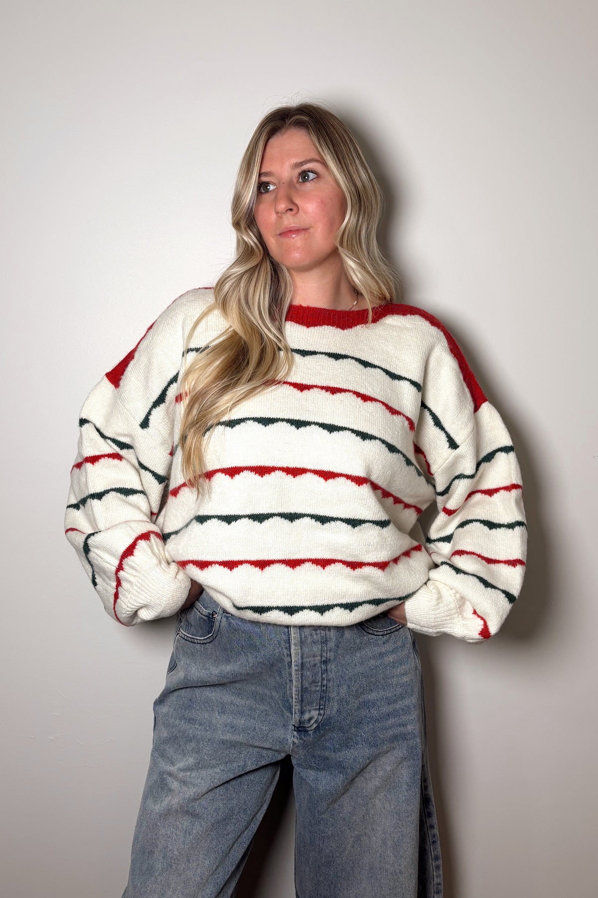 Person wearing a striped sweater and jeans against a plain background