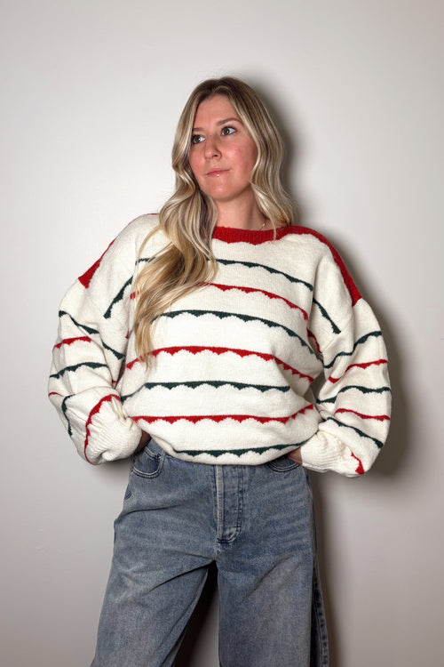 Person wearing a striped sweater and jeans against a plain background