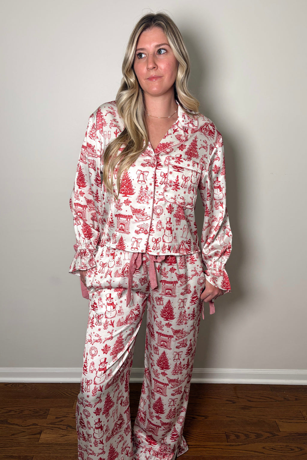 Woman wearing a red and white patterned pajama set against a plain wall.