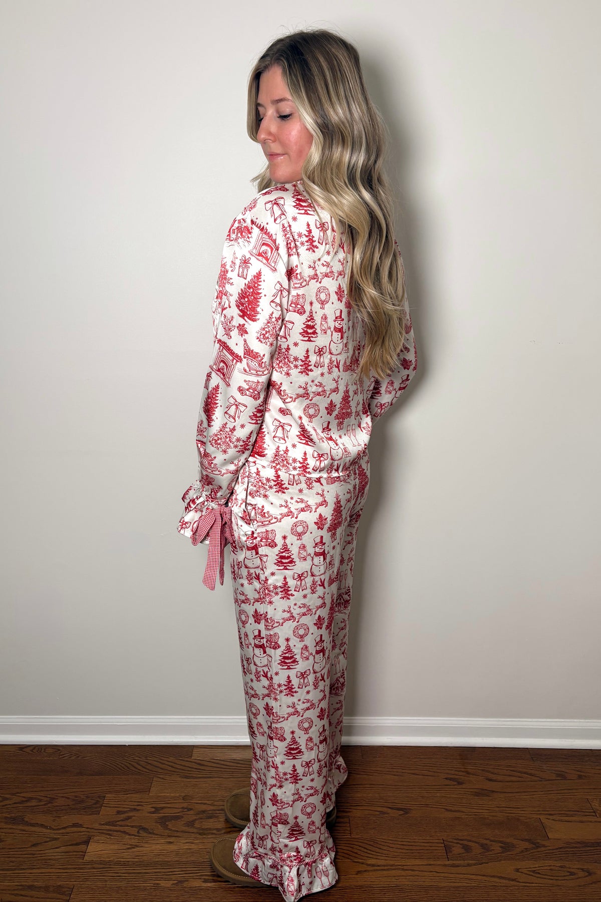 Woman wearing a red and white patterned pajama set against a plain wall.