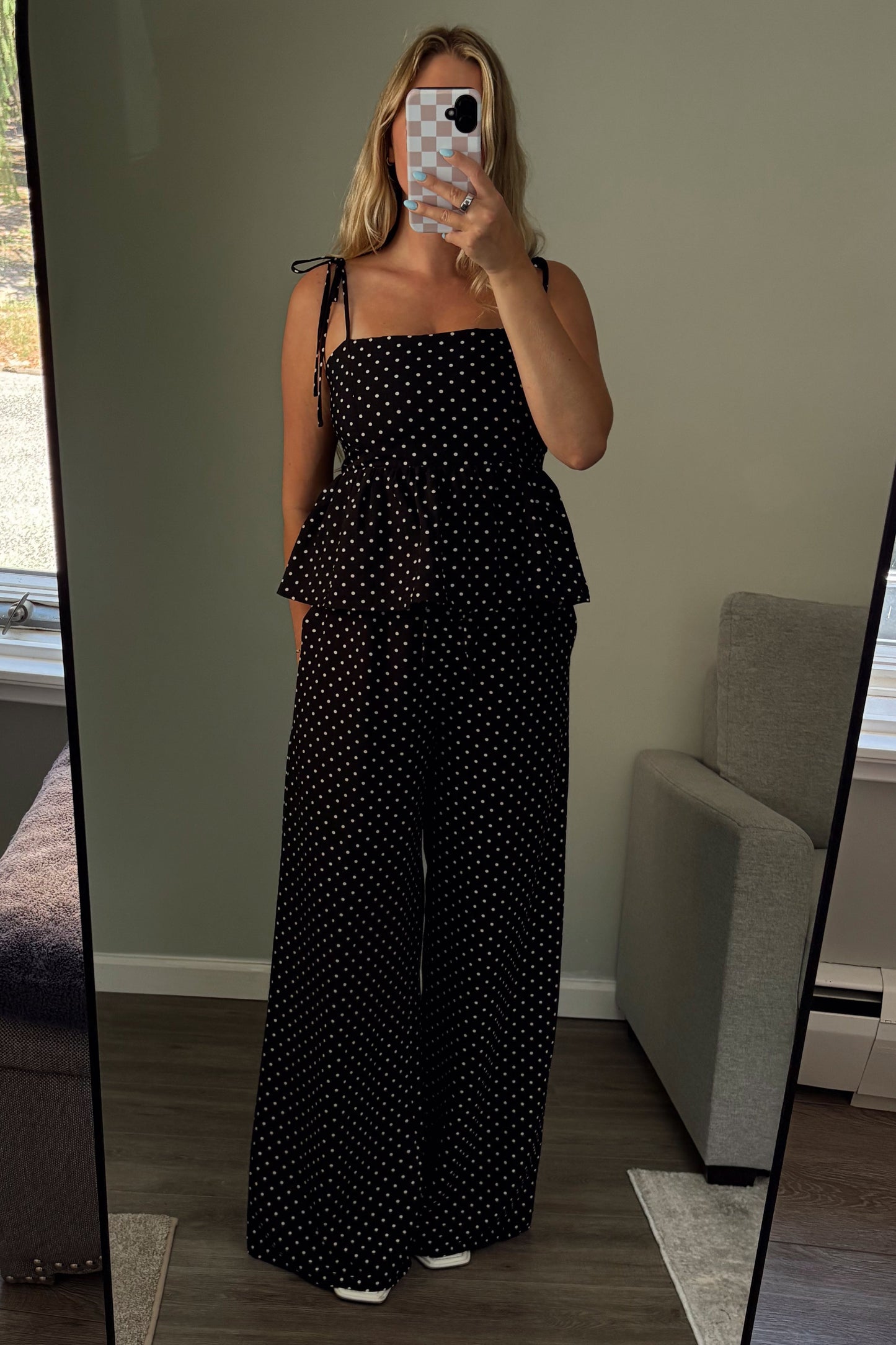 Person wearing a black polka dot outfit standing in front of a mirror.