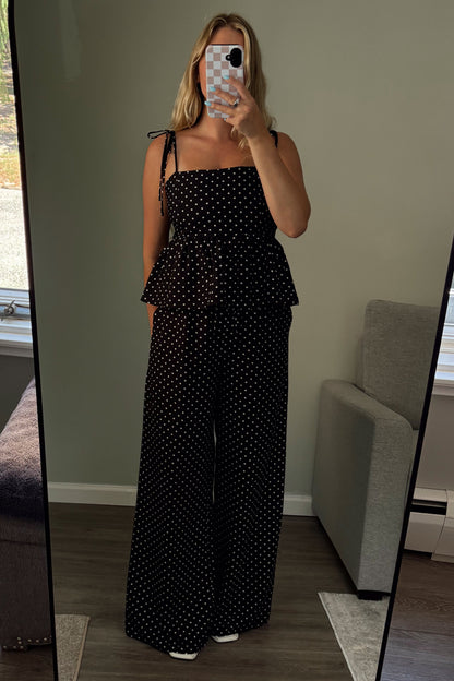 Person wearing a black polka dot outfit standing in front of a mirror.