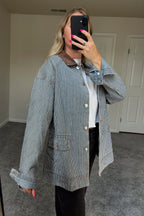 Angled mirror view of the Derby striped jacket showing the dropped shoulder, rolled cuff, and large front pocket.

