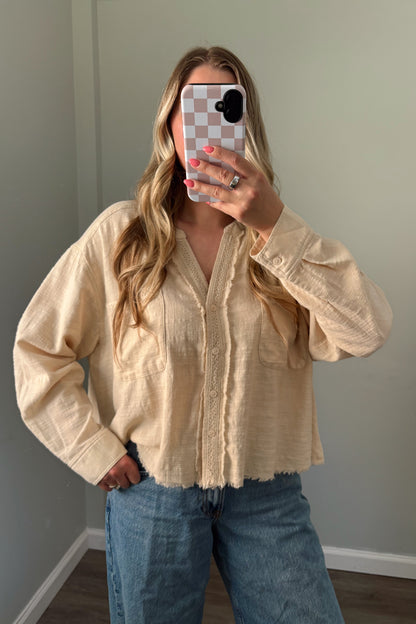 person wearing a cream buttondown top in a mirror photo