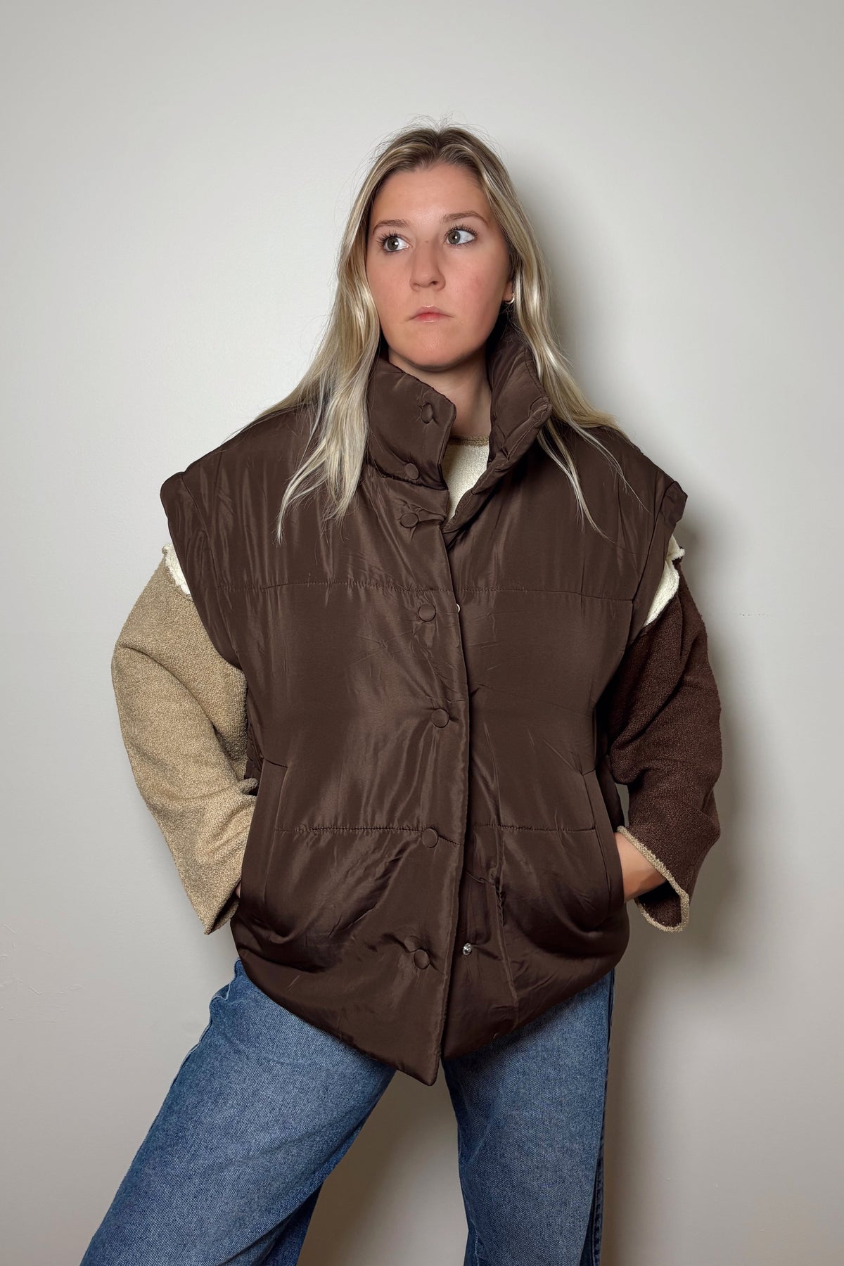 Parker brown puffer vest partially snapped closed, showing its mock neckline, padded panels, and side pockets.

