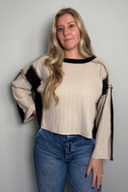 Three-quarter view of a model wearing the Sawyer colorblock knit top with exposed seam details and a cropped, boxy fit