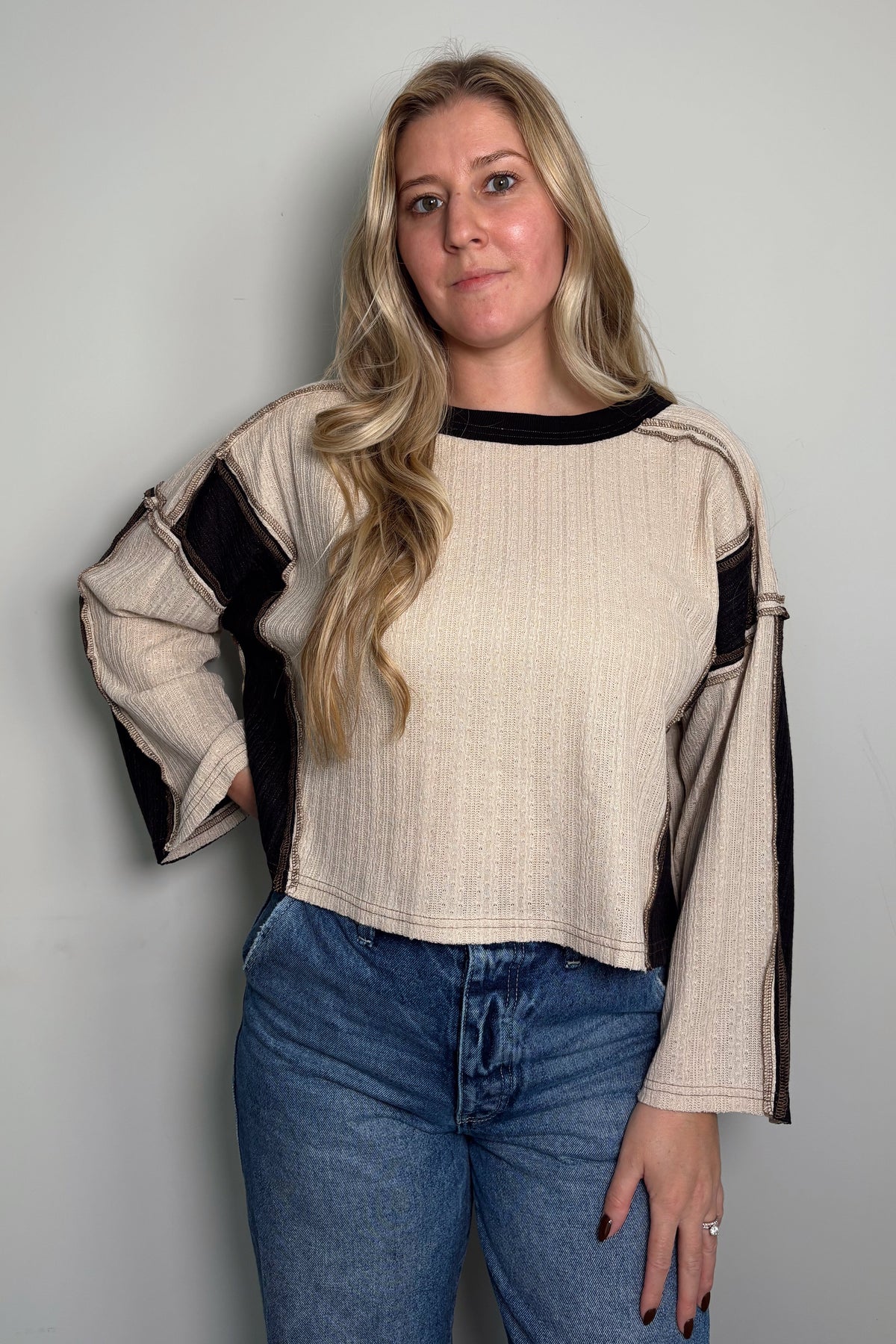 Three-quarter view of a model wearing the Sawyer colorblock knit top with exposed seam details and a cropped, boxy fit