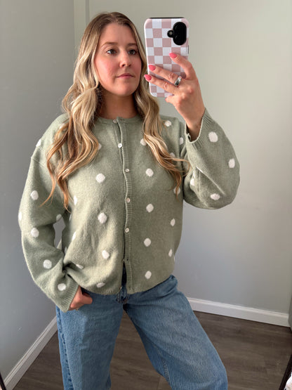 person wearing a sage green polka dot cardigan in a mirror photo
