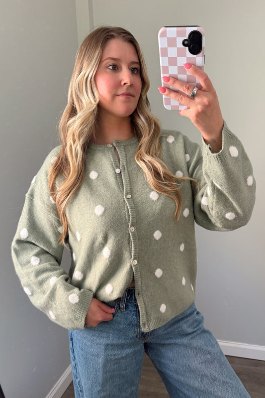 person wearing a sage green polka dot cardigan in a mirror photo