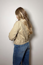 Back view of the Emery cropped cotton barn jacket showing its back seam and gathered hem above blue jeans.

