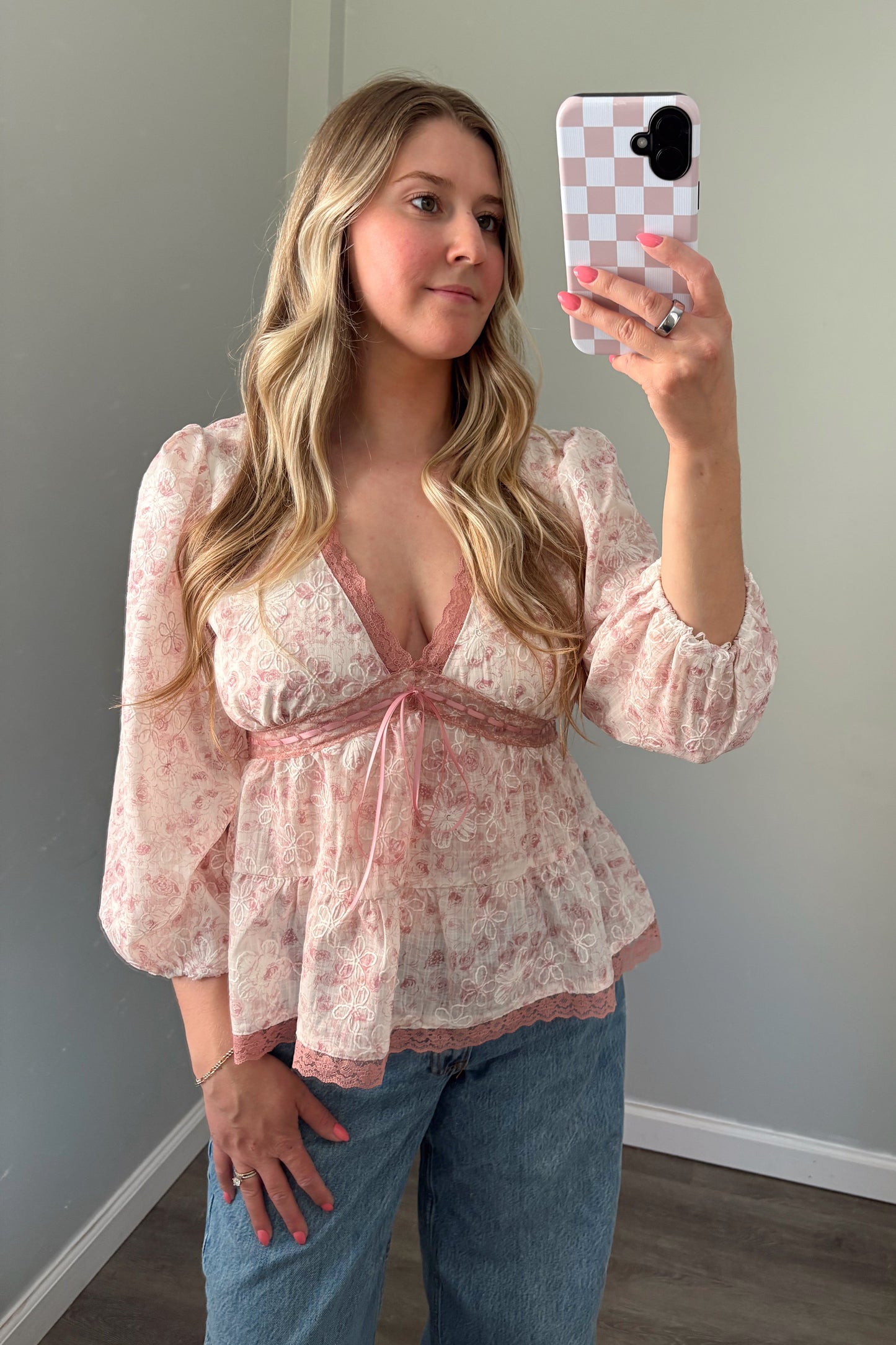 person wearing a babydoll pink blouse in a mirror photo