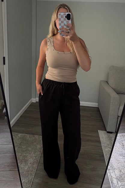 Person taking a mirror selfie in a room with a large mirror wearing black pants.
