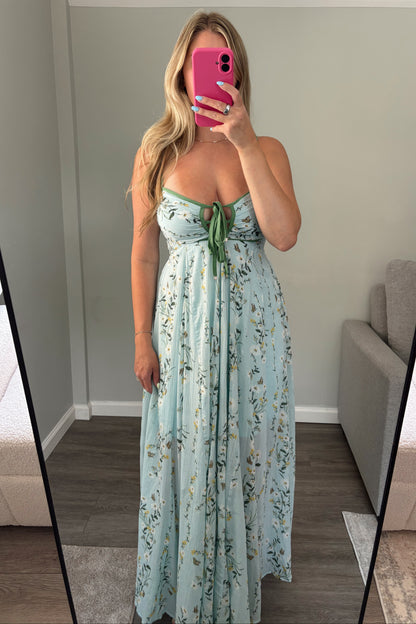 Woman holding a floral dress in front of a mirror