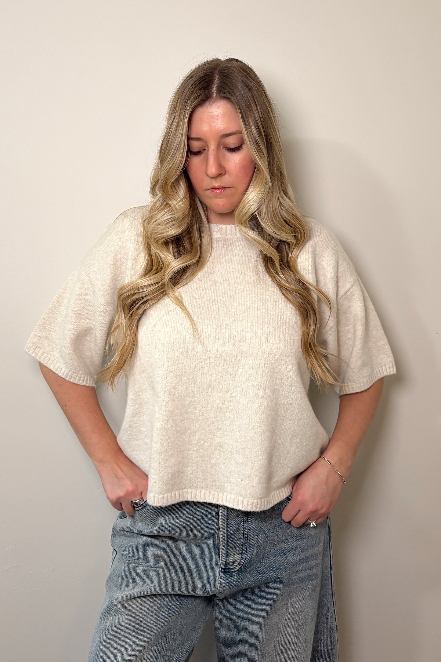 Person wearing a white oversized shirt and blue jeans against a plain background
