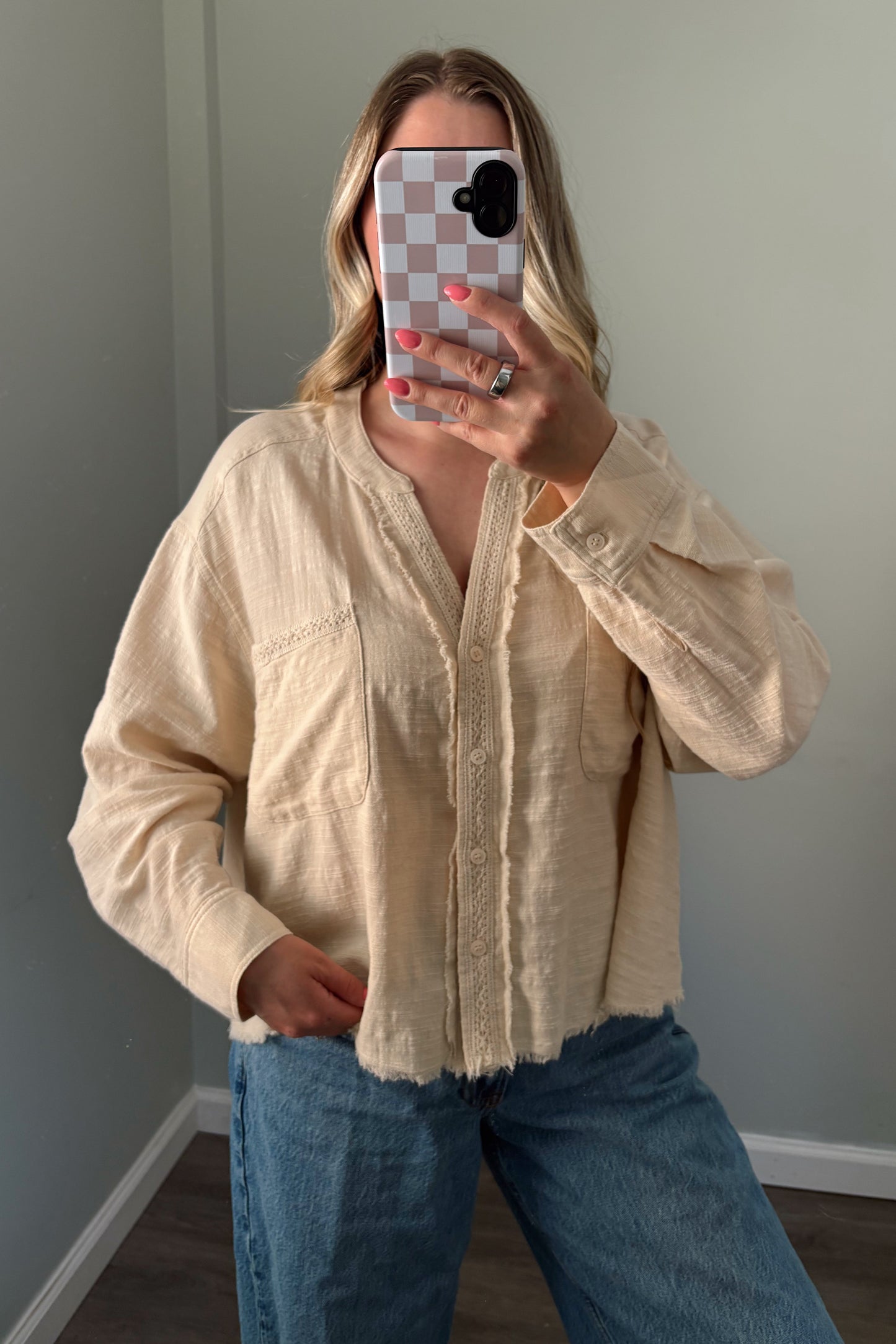 person wearing a cream buttondown top in a mirror photo