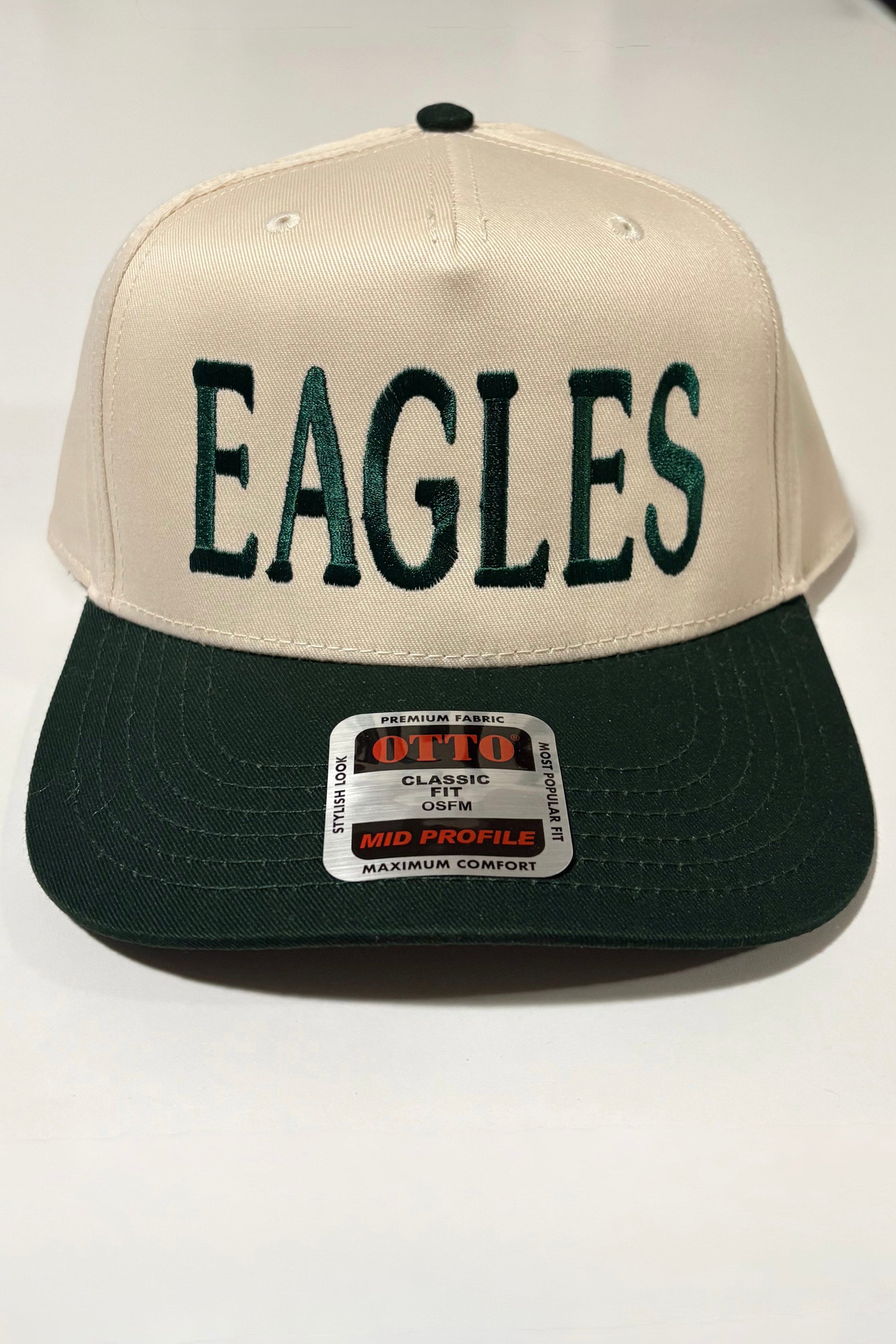 Beige and black cap with 'EAGLES' text on a white surface
