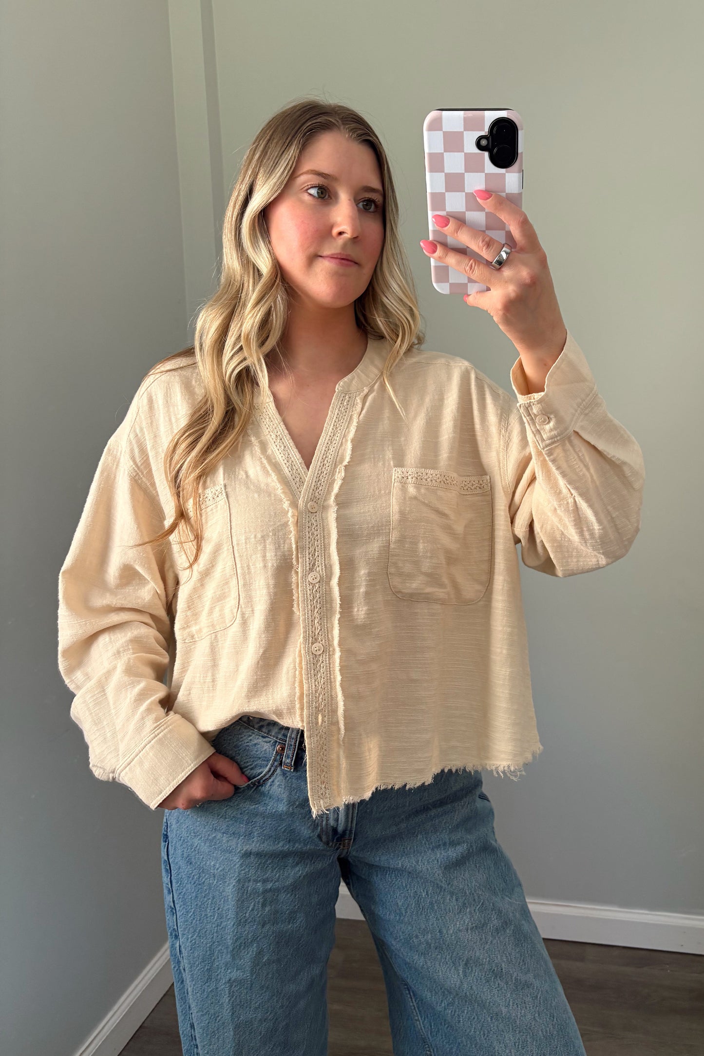 person wearing a cream buttondown top in a mirror photo