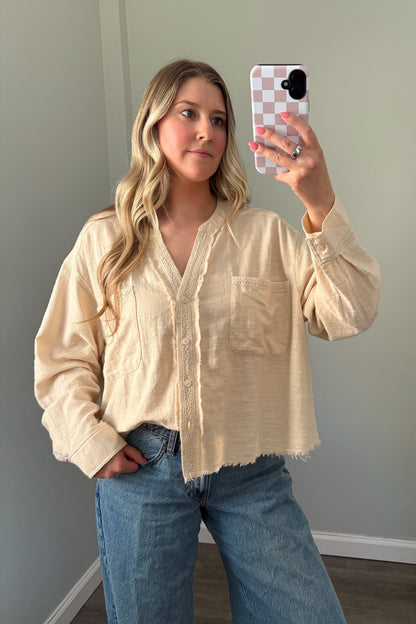 person wearing a cream buttondown top in a mirror photo
