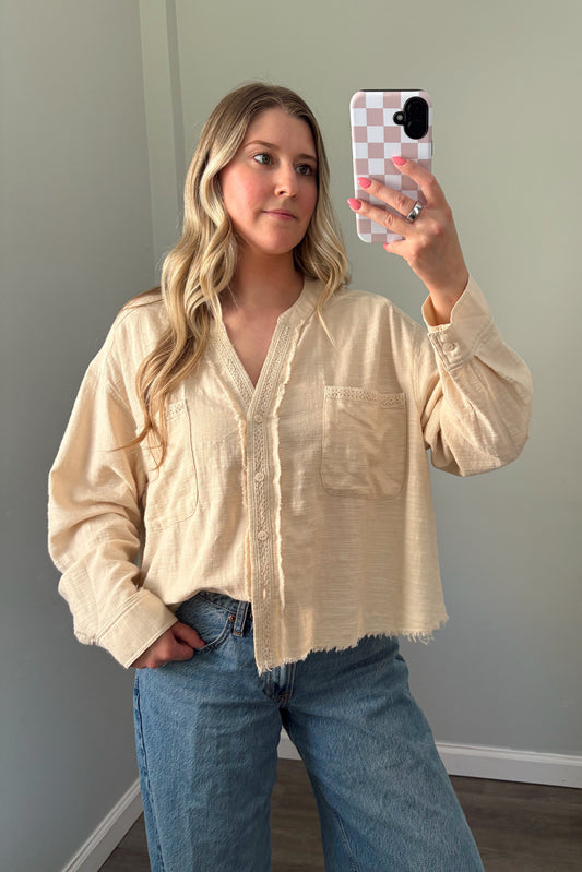 person wearing a cream buttondown top in a mirror photo