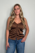 Model wearing the Delancey Polka Dot Cami in brown, a satin button-front cami with a lace-trim v-neckline, styled with blue jeans