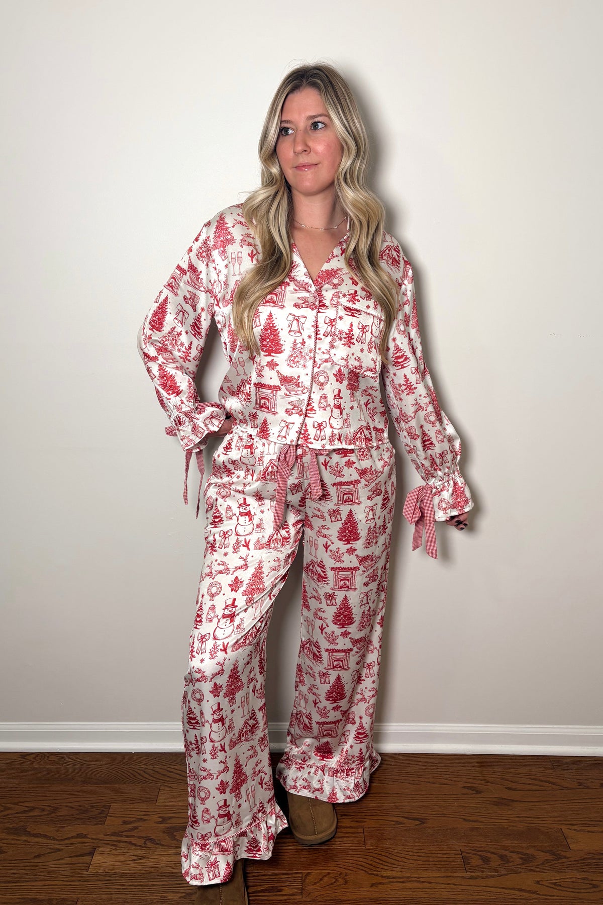 Woman wearing a red and white patterned pajama set against a plain wall.