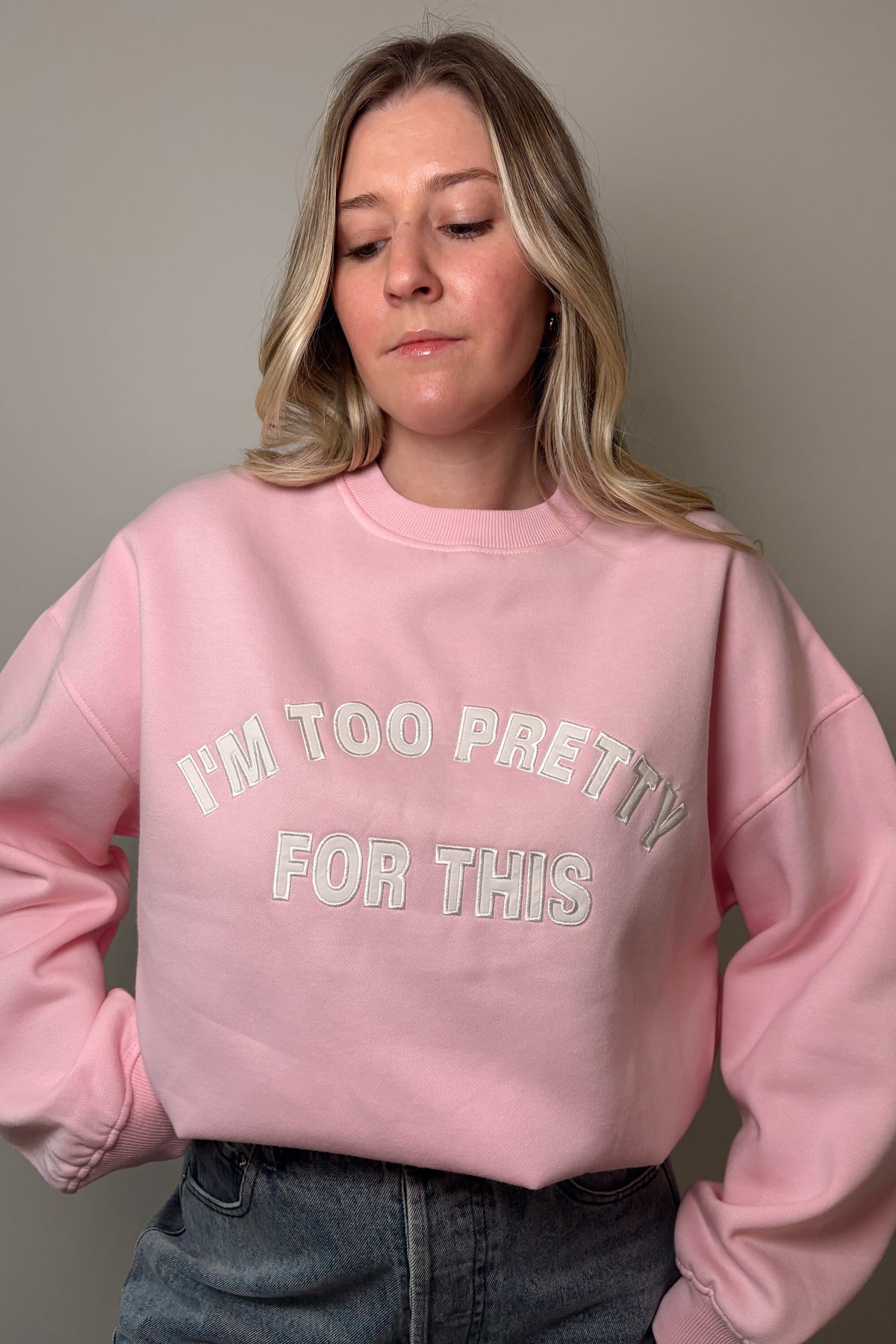 Close-up of the pink Too Pretty sweatshirt showing the embroidered I'm Too Pretty For This lettering and ribbed crew neckline.

