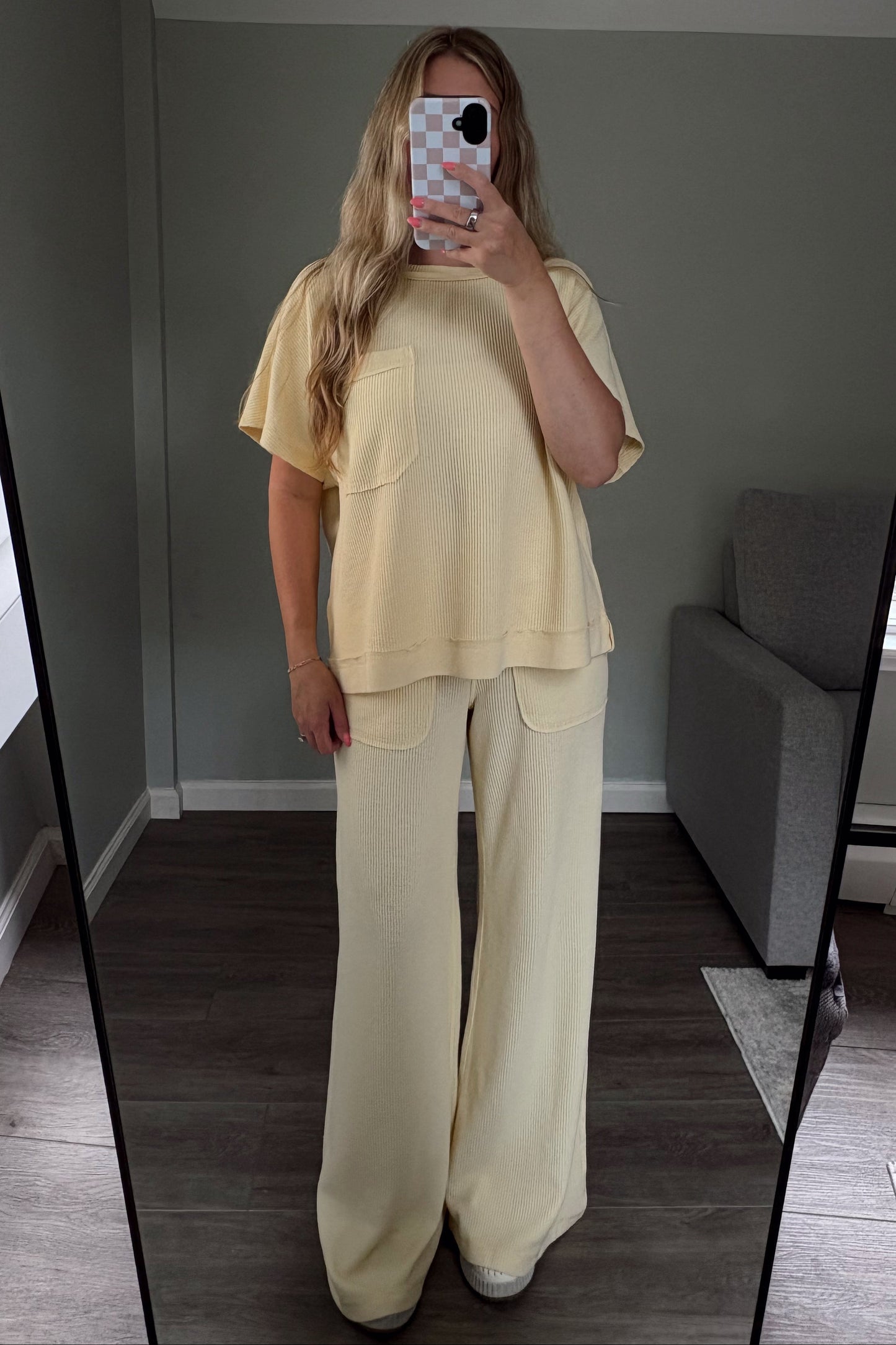 Person wearing a light-colored outfit taking a mirror selfie.