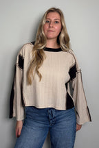 Front view of a model in the Sawyer cream and black colorblock knit top with long raglan sleeves and a ribbed boat neckline