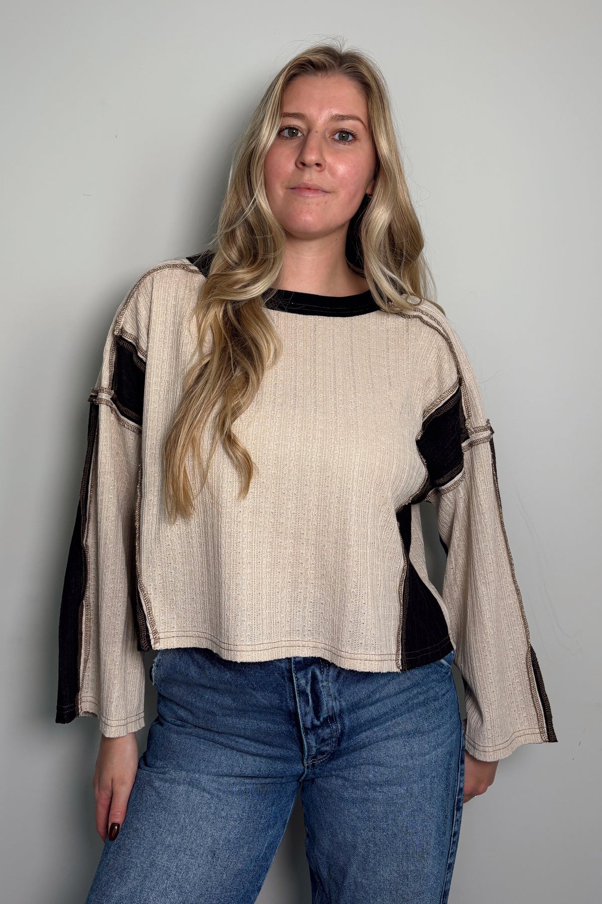 Front view of a model in the Sawyer cream and black colorblock knit top with long raglan sleeves and a ribbed boat neckline