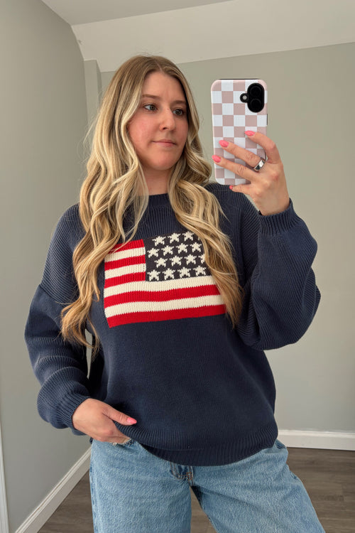 Front view of navy American flag sweater showing its relaxed fit and ribbed hem