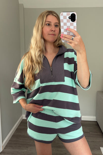 Woman taking a mirror selfie wearing a striped outfit in a room.