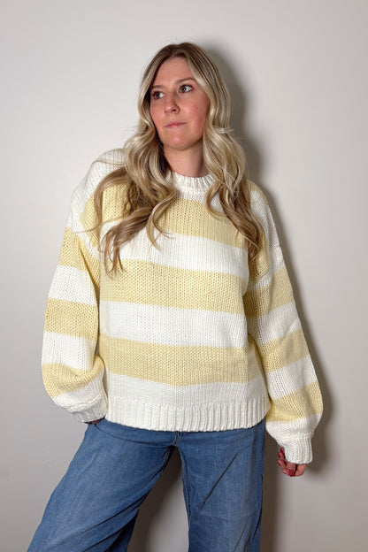 Person wearing a yellow and white striped sweater against a plain background