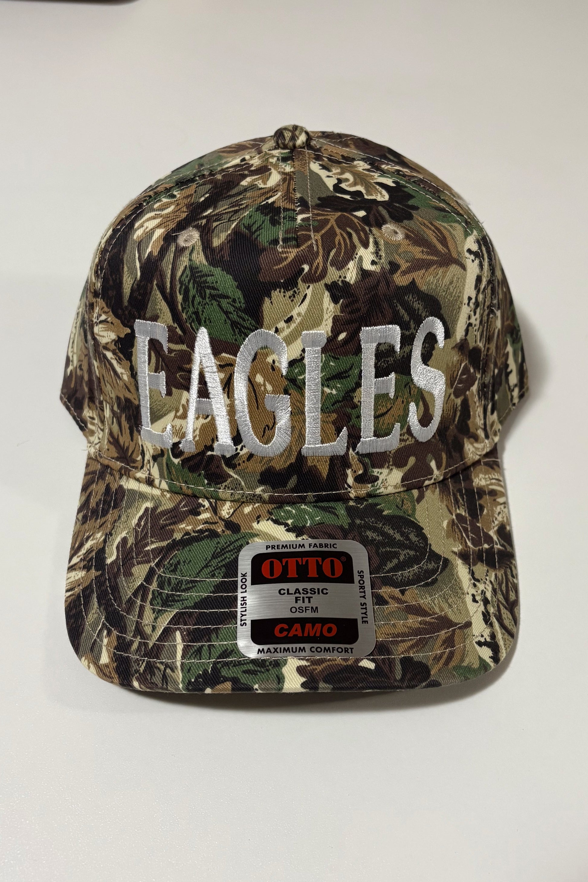 Camouflage cap with 'EAGLES' text on a white surface