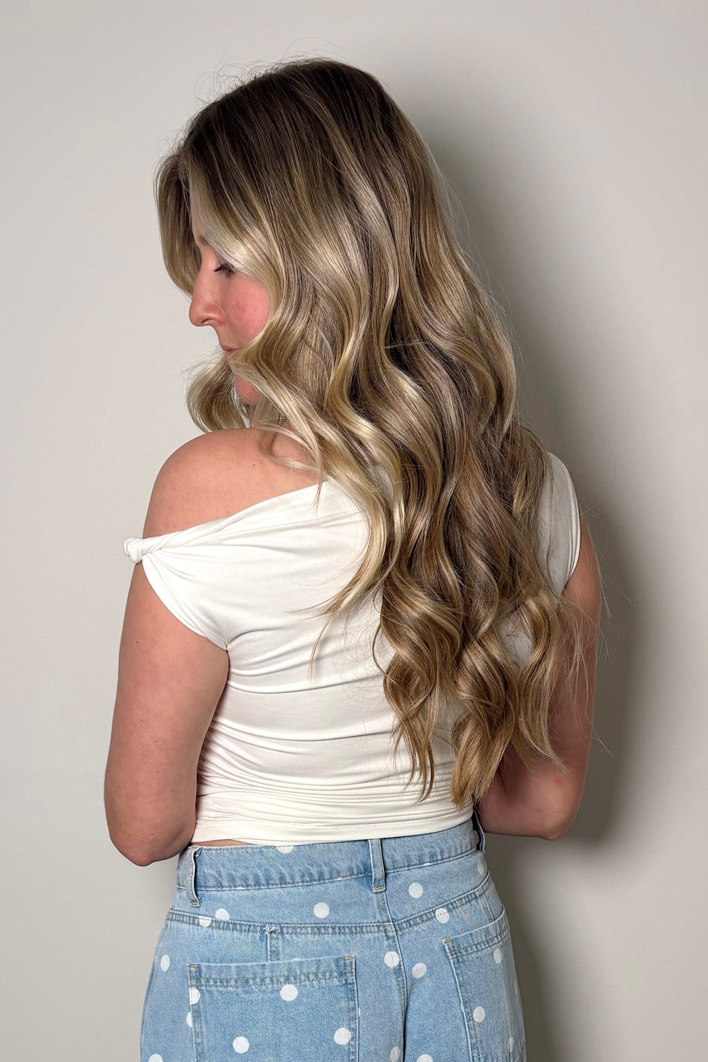 

Back view of the Clean Slate white top showing its off-the-shoulder detail and gathered sides above polka dot jeans.