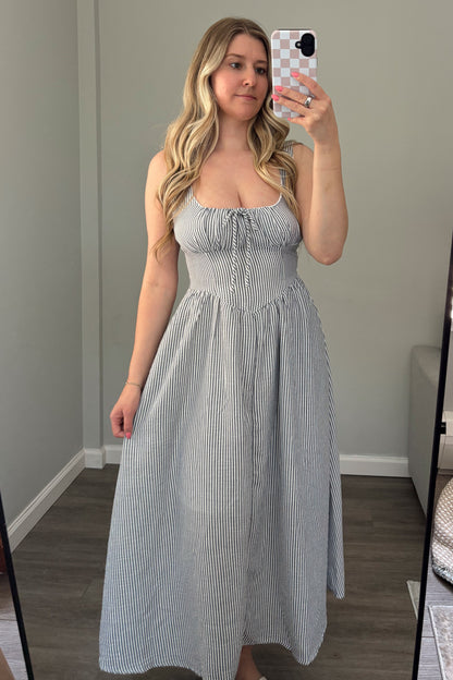 Woman taking a mirror selfie wearing a light blue dress in a room with a window.