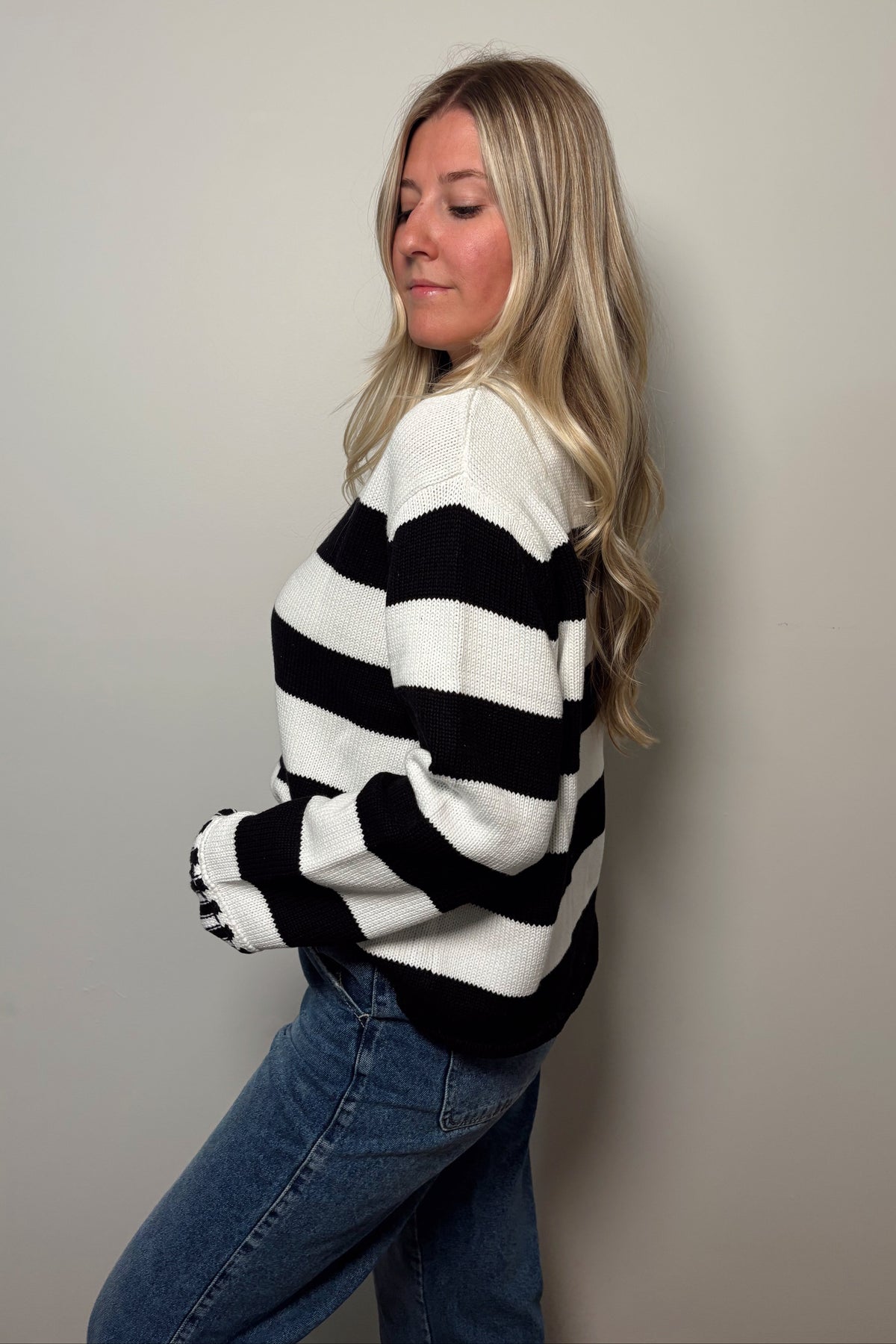Side and partial back view of the Sunday Brunch black and white striped sweater showing its loose silhouette and dark hem.

