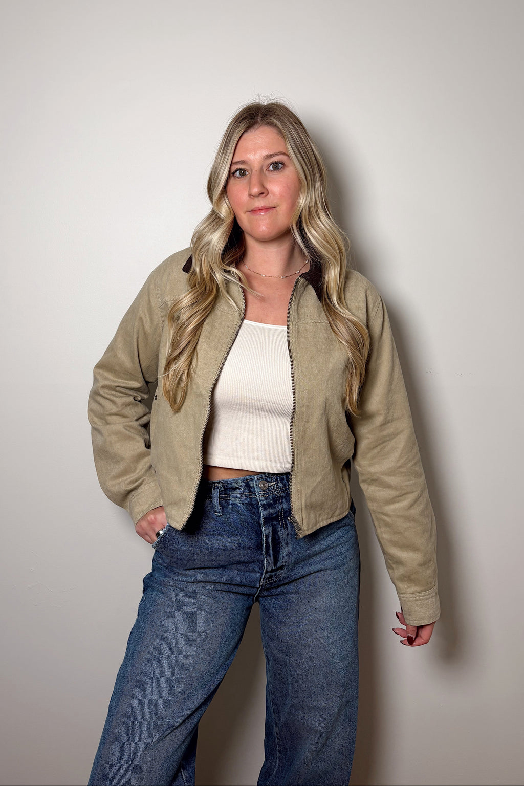Emery khaki cropped cotton canvas barn jacket worn open over a cream top and blue jeans, showing its contrast brown collar.

