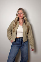 Emery khaki cropped cotton canvas barn jacket worn open over a cream top and blue jeans, showing its contrast brown collar.

