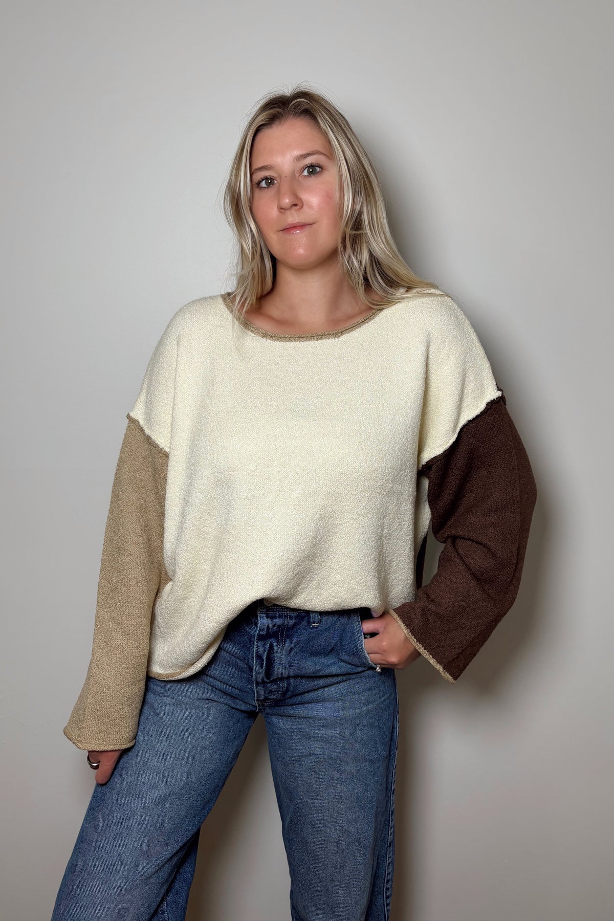 Brown Sugar colorblock sweater with a cream front and contrasting tan and chocolate brown sleeves styled with jeans