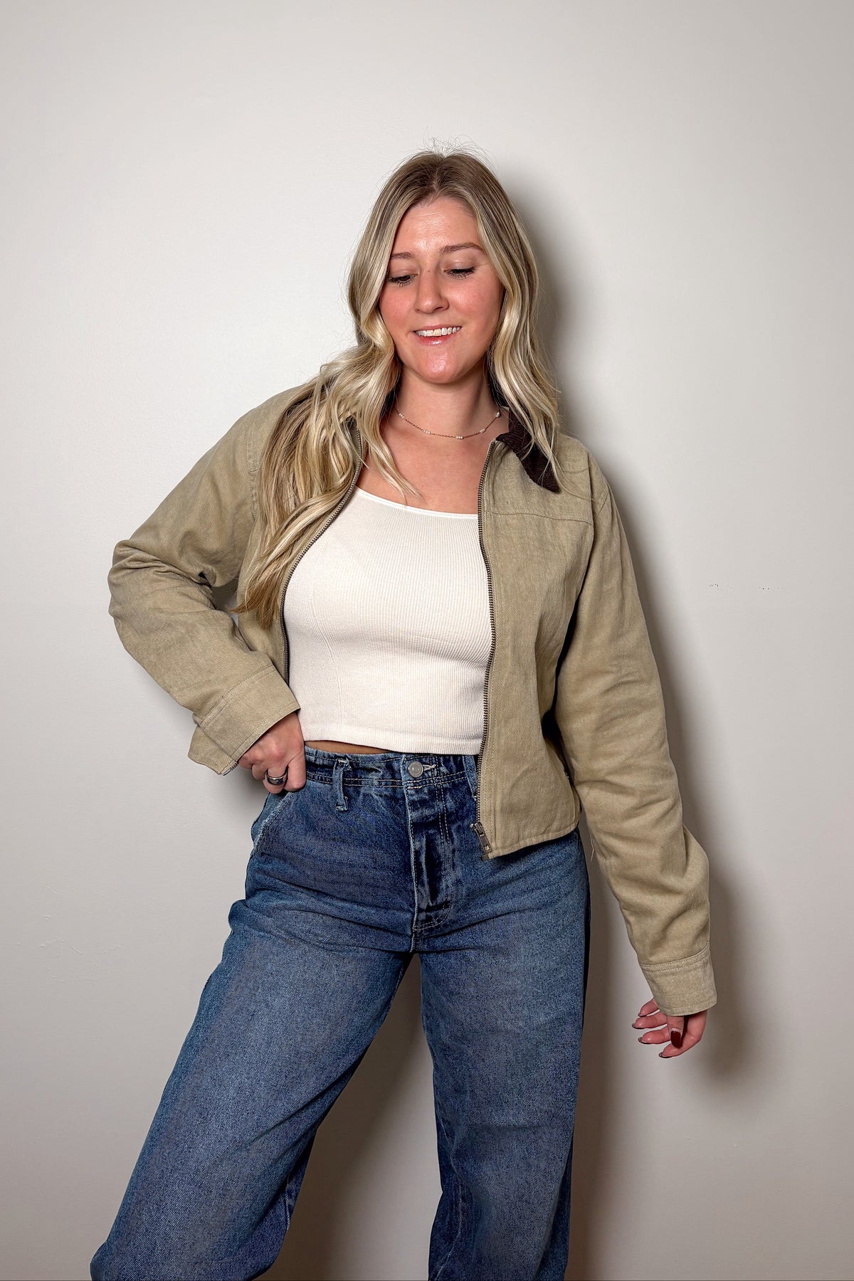 Front view of the Emery cropped barn jacket styled with a cream top and high-rise blue jeans, showing the open zipper.

