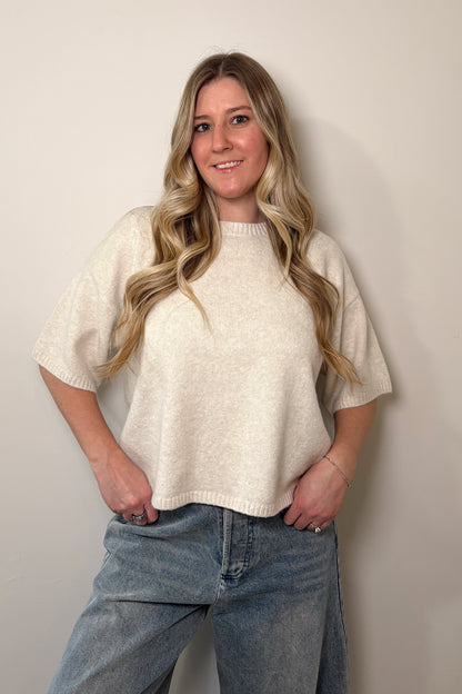 Woman wearing a white top and blue jeans against a plain background