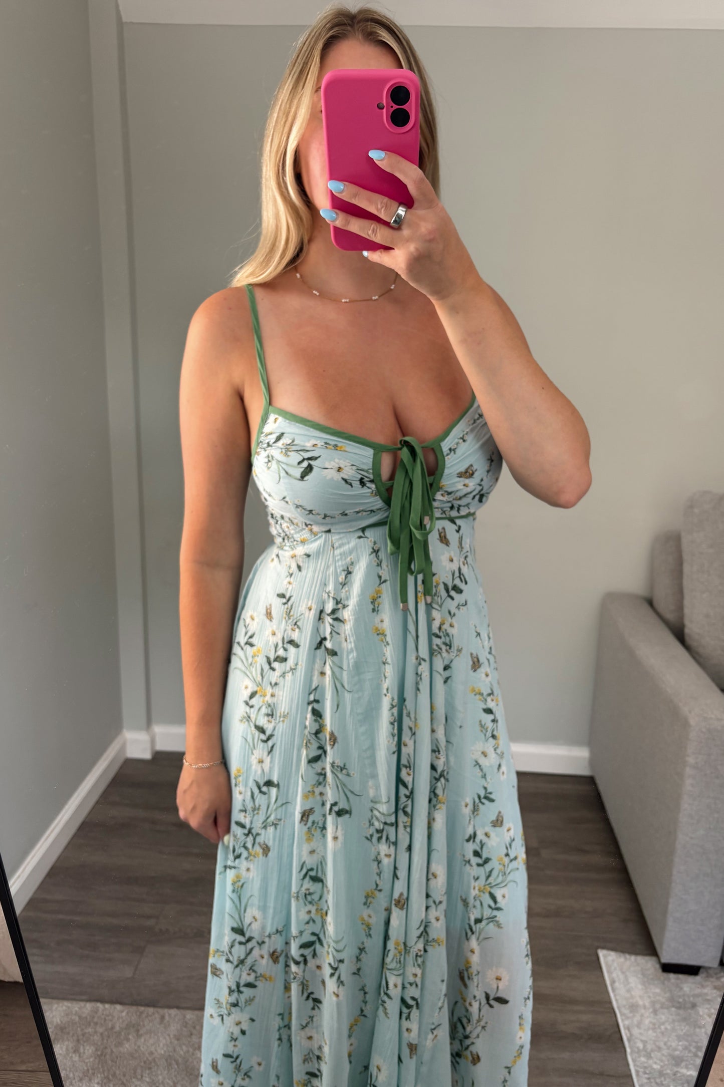 Woman taking a mirror selfie wearing a floral dress in a room.