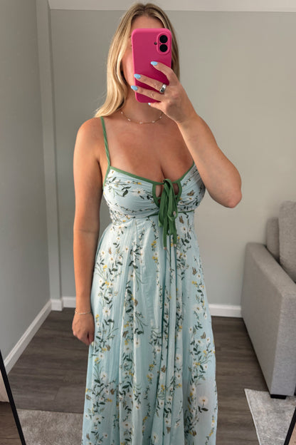 Woman taking a mirror selfie wearing a floral dress in a room.