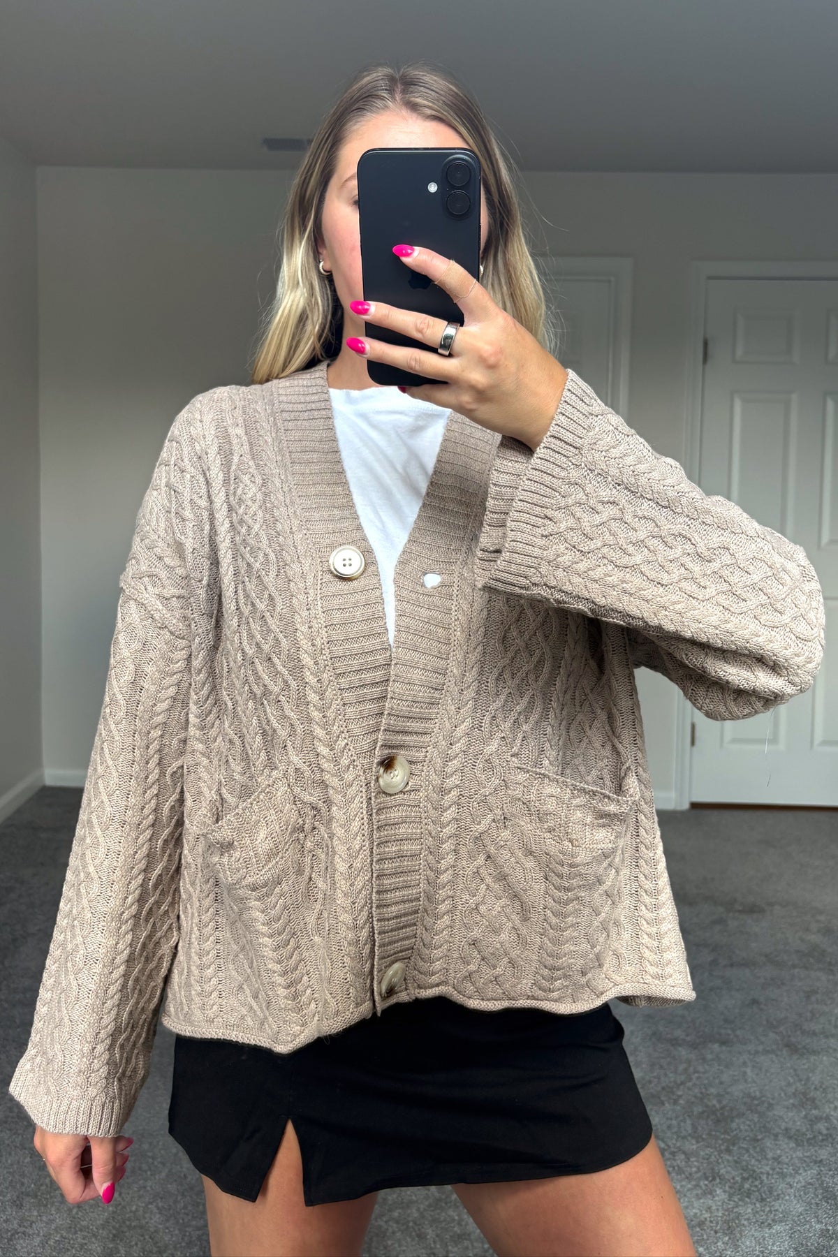 Front mirror view of the Fireside beige cardigan showing textured cable stitching, dropped shoulders, and long sleeves.

