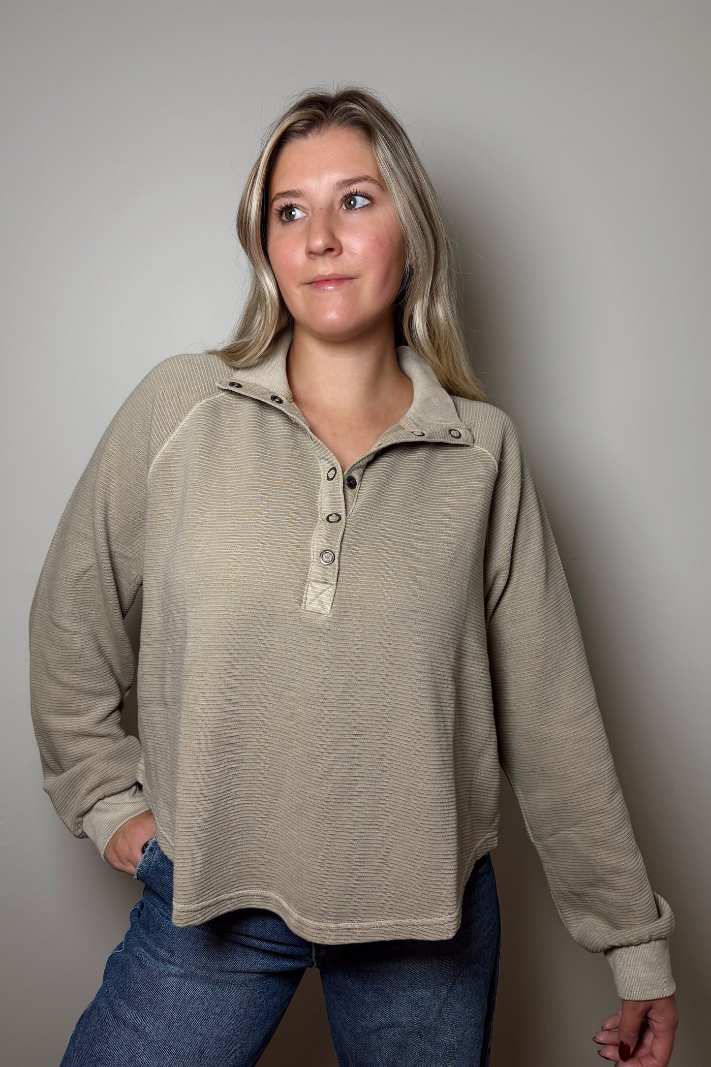 Woman wearing a beige pullover with a plain background