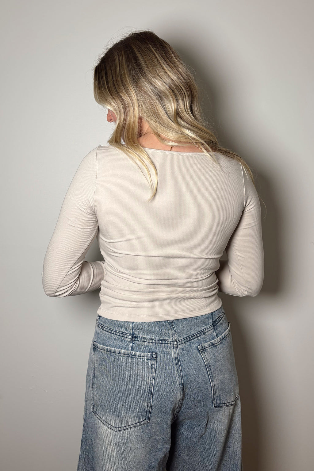 Back view of the Onyx bone ribbed top showing its fitted shape and straight hem above light-wash jeans.


