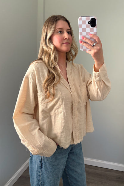 person wearing a cream buttondown top in a mirror photo