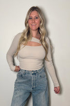 Front view of the Onyx bone cutout top showing its fitted ribbed silhouette and long sleeves, paired with denim.

