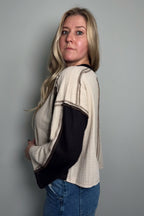 Back view of the Sawyer colorblock knit top showing the exposed raglan sleeve seams and black back panel